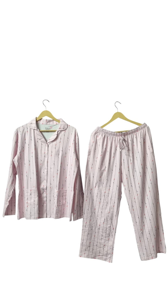 Night Suits By Aaka light pink loungewear set with vertical stripes and small floral accents on a dark grey wall