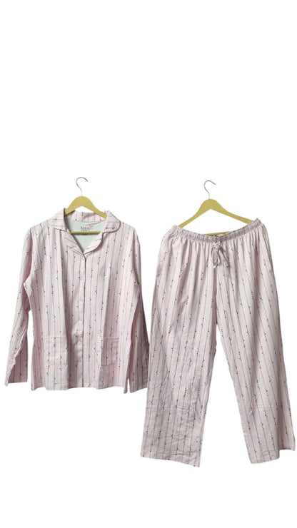 Night Suits By Aaka light pink loungewear set with vertical stripes and small floral accents on a dark grey wall