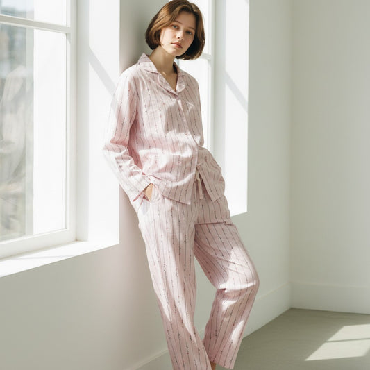 Night Suits By Aaka light pink pajama set with vertical stripes worn by a woman leaning against a bright window